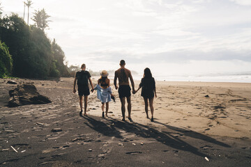 Unrecognizable friends walking on sandy beach