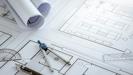 Yellow hard safety helmet hat and architectural blueprints and blueprint rolls and pencils pen,...