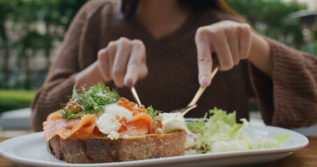 Obraz na płótnie Canvas Woman eat salmon toast at outdoor cafe