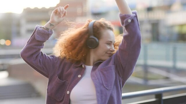 Woman dancing to music from headphones in the city