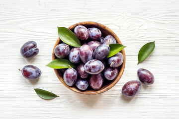 Food layout with plums in bowl with leaves. Top view