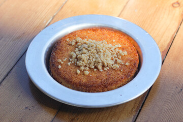 Traditional Turkish Dessert: Kunefe, Cheese and kadaif dessert with sherbet on wooden table . crumbled hazelnuts, isolated. Hatay cuisine.