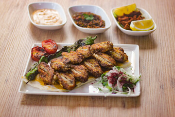 grilled chicken wings with vegetables, mezzes and salads on wooden table. turkish barbecue. 