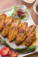 grilled chicken wings with vegetables, mezzes and salads on wooden table. turkish barbecue. close up.
