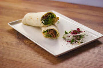 wrapped grilled meat lamb shish kebab with vegetables and salads on wooden table. turkish barbecue....