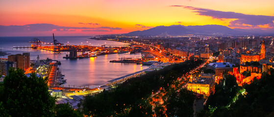 Aerial view of the city of Malaga at sunset with warm colors and city lights.