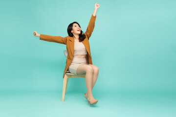 Attractive beautiful Asian businesswoman sitting on white modern chair and hands up raised arms...