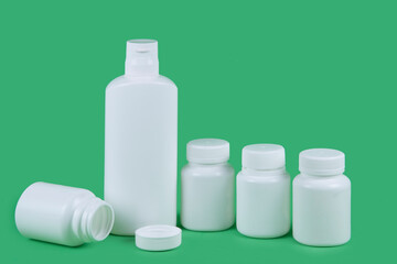 Medicine pill bottles. Vitamin package mockup on green background. Plastic supplement jar. Pharmaceutical product container. Pharmacy remedy pack.