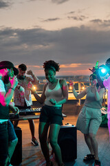 Young dancing friends surrounding African girl during disco at rooftop party - obrazy, fototapety, plakaty