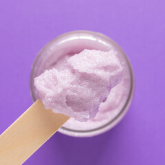 Cosmetic scrub for face and body on a wooden spatula on a lilac background. Beauty concept. Body treatment. Skin care.