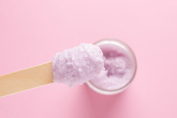Cosmetic scrub for face and body on a wooden spatula on a pink background. Beauty concept. Body treatment. Skin care.