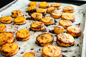 Sweet Caramel Cinnamon Baked Plantains: A parchment covered sheet pan of baked plantains covered in...