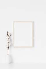 Wooden frame mockup on the wall with a cotton branch decoration.