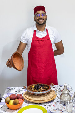 A Moroccan cook presents his plate of lamb with plums on the table

