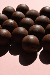 Close-up of round chocolates with dark shadows and pink background