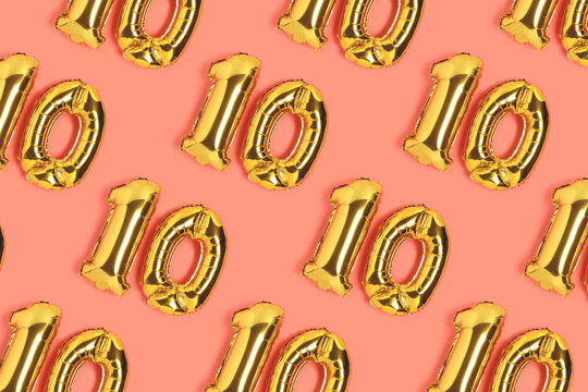 Numbers 10 golden balloons pattern. Ten years anniversary celebration layout on a coral backdrop.
