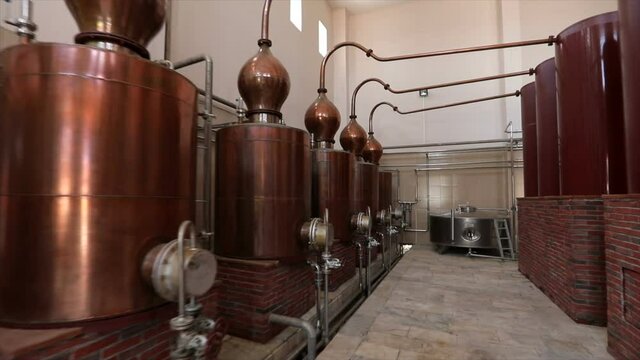 Large stainless steel brandy distilling tanks. Silos for wine and cognac fermentation . Steel barrels for fermentation of wine in winemaker factory . Dolly , ronin movement a long row of spirit vats .