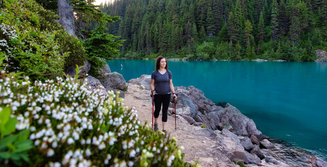 Fototapeta premium Adventurous White Caucasin Adult Woman Hiking on a trail in Canadian Nature. Sunset Sky. Garibaldi Lake Hike near Whistler and Squamish, British Columbia, Canada.