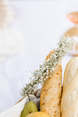 The concept of a romantic holiday. Picnic on the pier against the background of the river. Baguette in a jute basket. A wreath of a gypsophila flower.