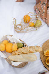 The concept of a romantic holiday. Picnic on the pier against the background of the river. Baguette in a jute basket. Champagne glasses. fruits, apricots and pears. wooden board and white sheet