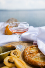 Picnic. fruit and a glass saucer with pink wine on a white sheet. The concept of a romantic holiday. a cozy picnic in nature.