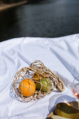 The concept of a romantic holiday. Fruit in a string bag. straw hat in eco-style. Picnic on the background of the river.