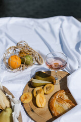 Picnic. fruit and a glass saucer with pink wine on a white sheet. The concept of a romantic holiday. a cozy picnic in nature.