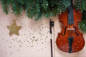 Fototapeta na wymiar Old violin and fiddlestick, fir-tree branches with Christmas decor. Christmas, New Year's concept. Top view, close-up on pastel color background.