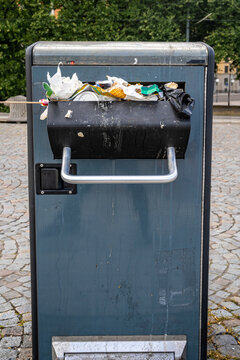 Outdoor steel trash can full of overflowing garbage waste and filth in Stockholm City.