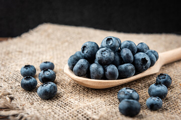 Blueberry in wooden spoon on dark wooden background.
