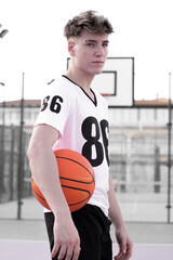 Fototapeta premium Chico joven jugando al baloncesto en una pista de juego con el balón