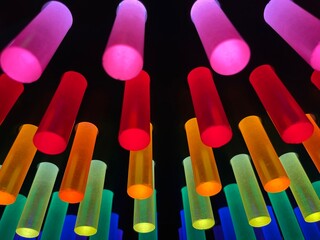 Defocused rainbow colored glowing glass sticks on black background