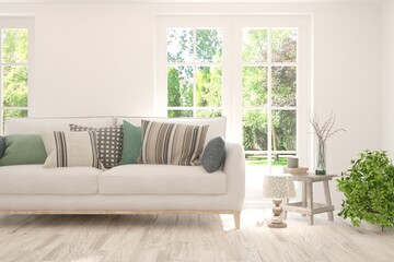 Fototapeta premium Stylish room in white color with sofa and summer landscape in window. Scandinavian interior design. 3D illustration