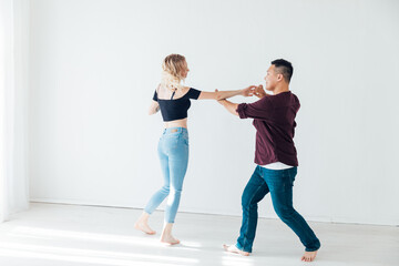 beautiful man and woman dancing bachata to music in a white room