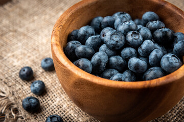 Blueberry in wooden bowl on dark wooden background.