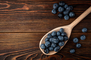 Blueberry in wooden spoon on dark wooden background.