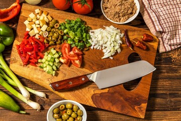 Tasty tuna salad with vegetables on wooden table. Vegetable salad with tuna. Preparing a healthy vegetable salad with fish. Diet food for athletes.