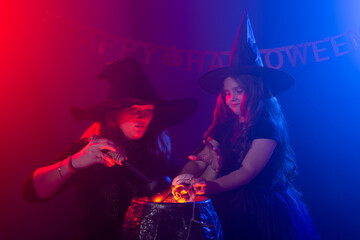 Funny child girl and woman in witches costumes for Halloween.