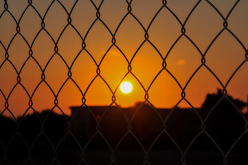 Sunset behind bars. An example of inaccessible happiness