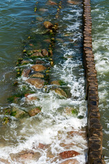 A breakwater made of logs cuts through the sea wave