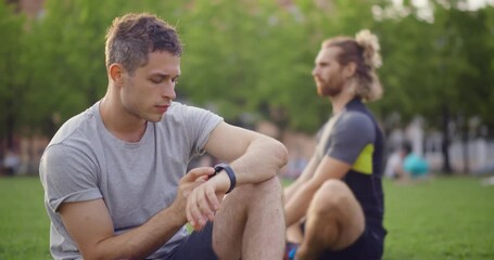 Young caucasian man checking health data on smartwatch after exercise at park - Powered by Adobe