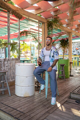 Chico joven atractivo tatuado con camisa de flores en local de playa en dia soleado de verano