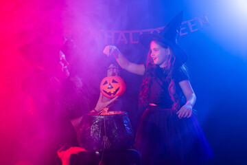 Funny child girl and woman in witches costumes for Halloween with pumpkin Jack.