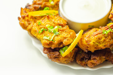 Delicious onion bhaji fritters served on ceramic plate with white dip