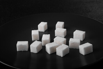 Several lumps of sugar on a black plate.