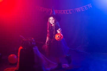 Funny child girl in witch costume for Halloween with pumpkin Jack.