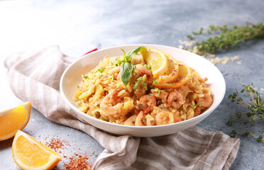 Healthy food. A seafood dish. Risotto with shrimp, scallops, lemon and fresh herbs in a white plate on a bright table. Background image, copy space