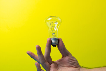 Hand holds an incandescent lamp on a colored background. Idea and development concept