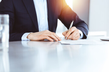 Businessman using silver pen for contract signing at the glass desk in modern office. Unknown male entrepreneur at workplace, close-up