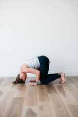 woman entering headstand pose in vinyasa yoga in studio